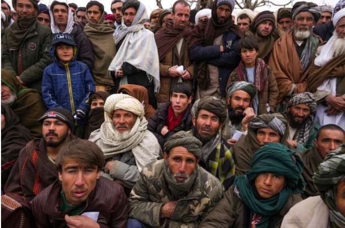 Hundreds of Afghan men gather to receive humanitarian aid.